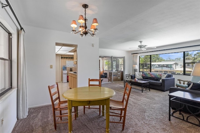 dining area featuring light colored carpet and ceiling fan with notable chandelier