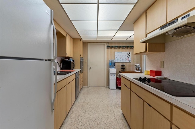 kitchen featuring under cabinet range hood, stainless steel appliances, light brown cabinetry, and light countertops