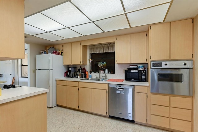 kitchen with light brown cabinetry, a sink, black appliances, and light countertops
