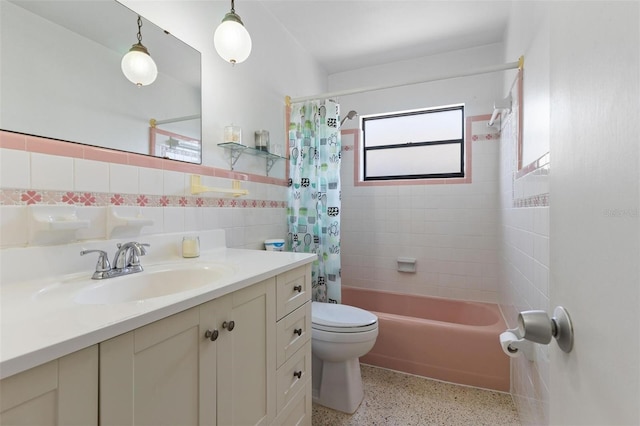 full bath featuring vanity, toilet, tile walls, speckled floor, and shower / bath combo
