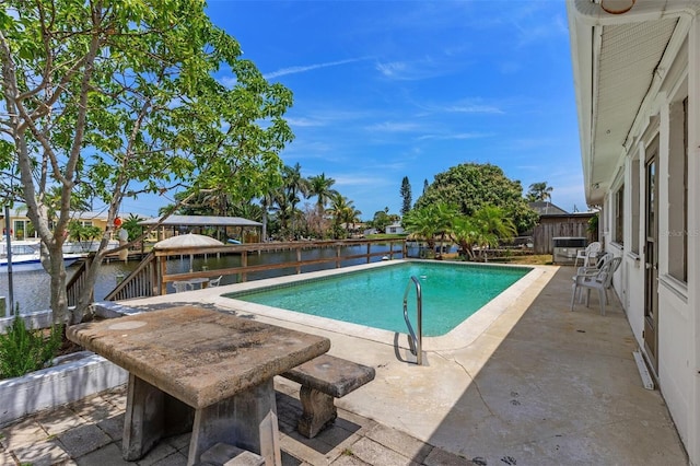 view of pool featuring a fenced in pool, a water view, and a patio area