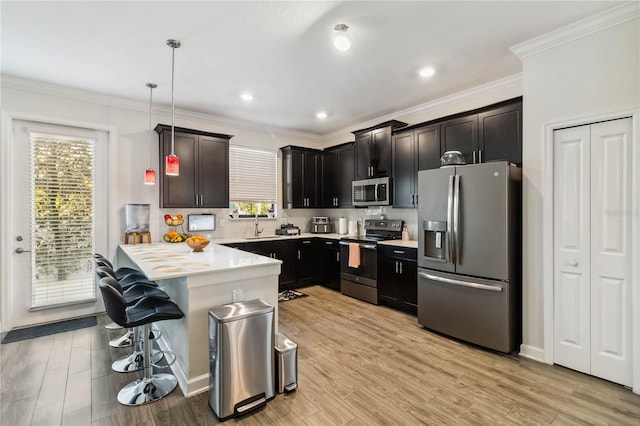 11150 Whistling Pine Way, Orlando, FL 32832 - kitchen with light wood finished floors, a breakfast bar area, appliances with stainless steel finishes, a peninsula, and ornamental molding