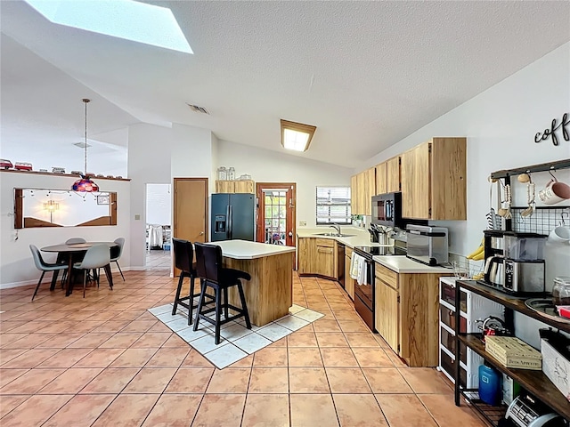 1007 Gammage Pt, Oviedo, FL 32765 - kitchen with black appliances, lofted ceiling, a kitchen island, a kitchen breakfast bar, and light countertops
