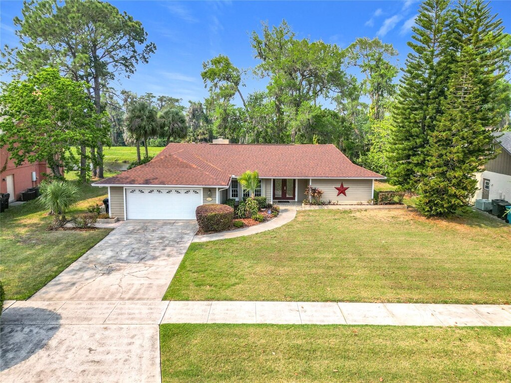 4423 Real Ct, Orlando, FL 32808 - single story home featuring a front yard, a chimney, concrete driveway, and an attached garage
