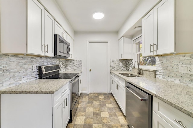 5144 Orange Ave, Winter Park, FL 32792 - kitchen with appliances with stainless steel finishes, a sink, stone finish flooring, and white cabinetry
