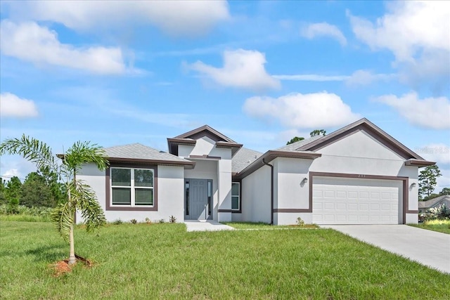 prairie-style house featuring a garage, concrete driveway, a front lawn, and stucco siding
