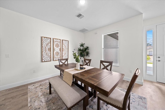 dining room featuring light wood finished floors, baseboards, and visible vents