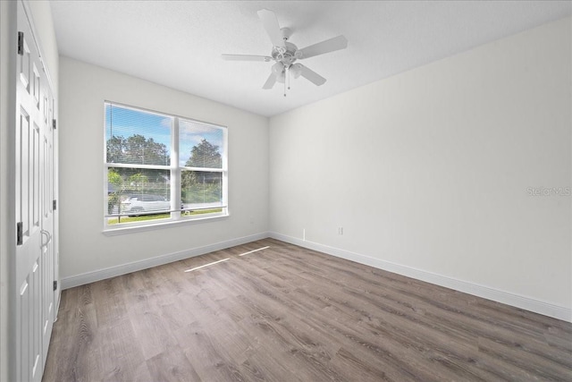 empty room featuring baseboards, wood finished floors, and ceiling fan