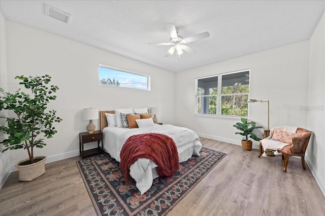 bedroom featuring baseboards, a ceiling fan, visible vents, and light wood-style floors