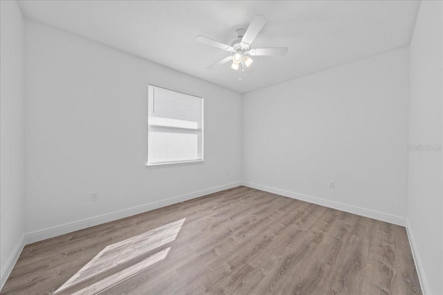 unfurnished room featuring baseboards, wood finished floors, and ceiling fan