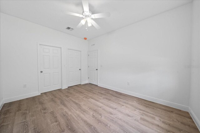 unfurnished bedroom featuring wood finished floors, visible vents, baseboards, and ceiling fan
