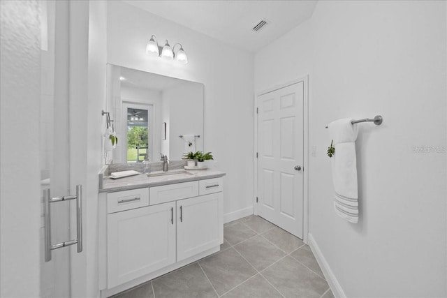 bathroom featuring baseboards, vanity, tile patterned floors, and visible vents