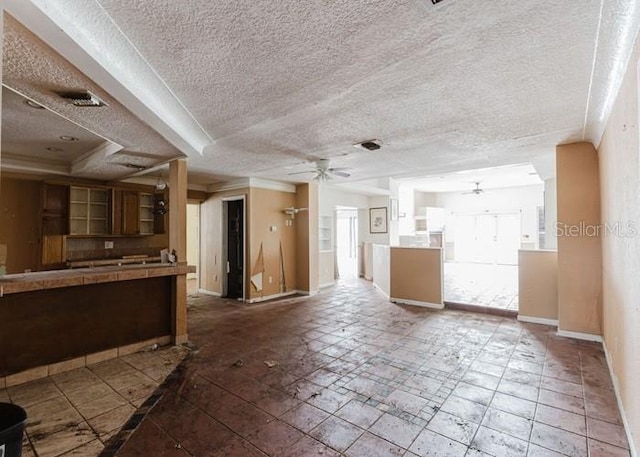 11120 5th St E, Treasure Island, FL 33706 - unfurnished living room with a ceiling fan, a textured ceiling, baseboards, and healthy amount of natural light
