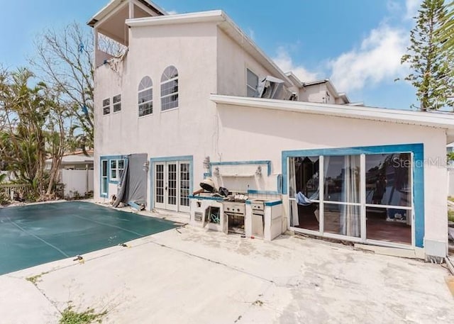 11120 5th St E, Treasure Island, FL 33706 - back of house with a patio, french doors, a covered pool, and stucco siding