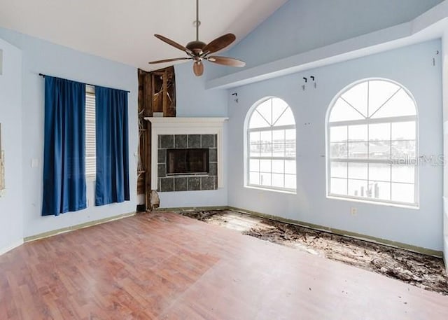 11120 5th St E, Treasure Island, FL 33706 - unfurnished living room with ceiling fan, a tile fireplace, wood finished floors, and high vaulted ceiling