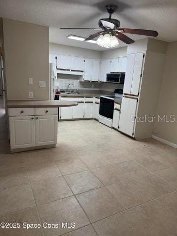 kitchen featuring a ceiling fan, stainless steel microwave, a sink, range with electric stovetop, and white cabinets