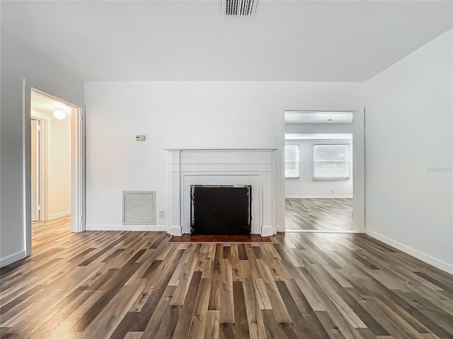 unfurnished living room featuring wood finished floors, baseboards, and a fireplace with flush hearth