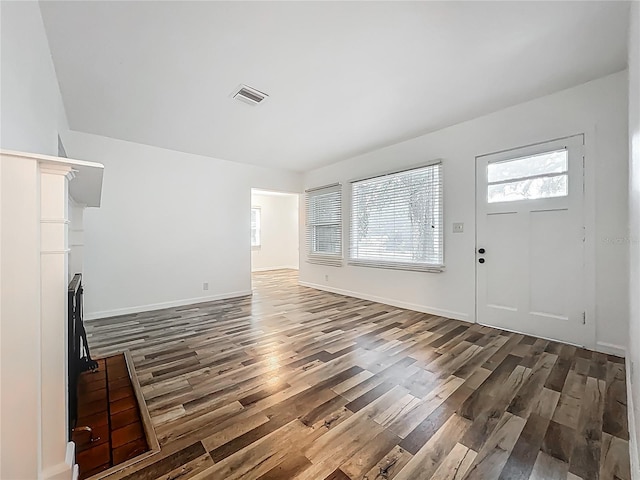 unfurnished living room with dark wood-style flooring and baseboards