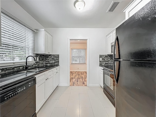 kitchen featuring black appliances, a sink, dark countertops, tasteful backsplash, and light tile patterned floors