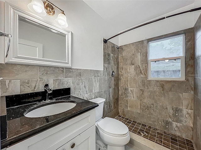 bathroom featuring tiled shower, tile walls, vanity, and toilet