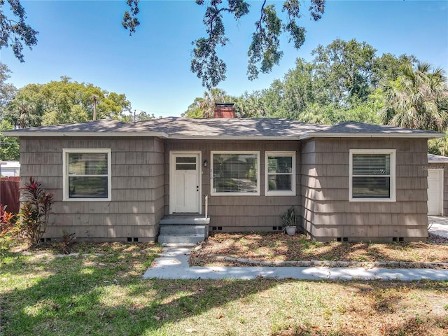 bungalow featuring crawl space, a chimney, a front yard, and roof with shingles