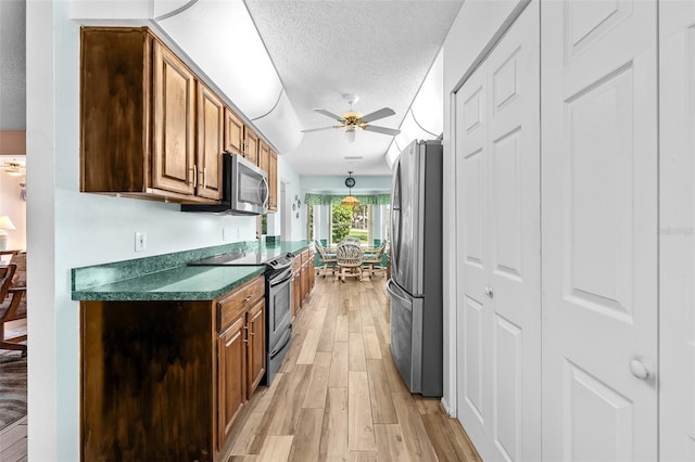 2436 Deer Trail Ln, Spring Hill, FL 34606 - kitchen with appliances with stainless steel finishes, ceiling fan, light wood-style flooring, dark countertops, and a textured ceiling