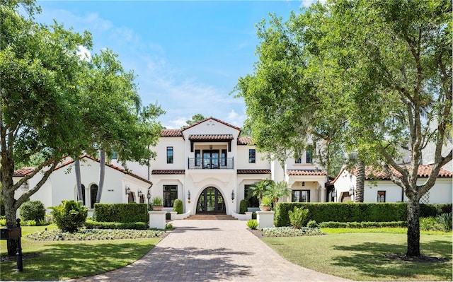 10138 Enchanted Oak Dr, Golden Oak, FL 32836 - mediterranean / spanish-style home featuring a tiled roof, stucco siding, a front lawn, a balcony, and french doors