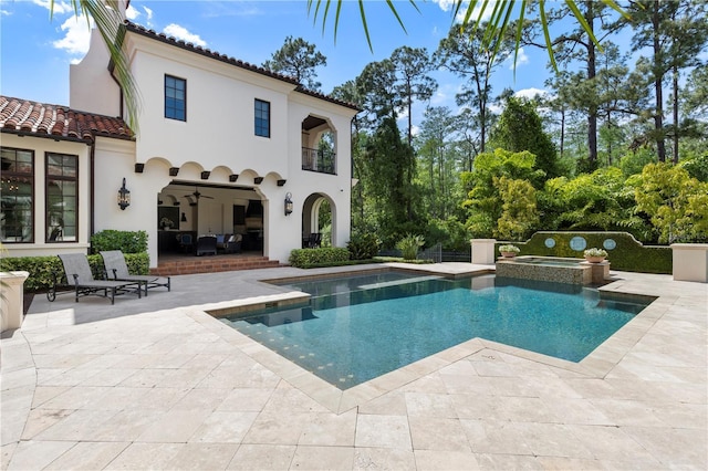 10138 Enchanted Oak Dr, Golden Oak, FL 32836 - rear view of house featuring a patio area, a tiled roof, a pool with connected hot tub, stucco siding, and a balcony