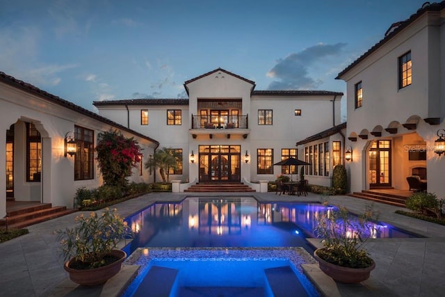 10138 Enchanted Oak Dr, Golden Oak, FL 32836 - rear view of property with a patio area, a pool with connected hot tub, stucco siding, french doors, and a balcony