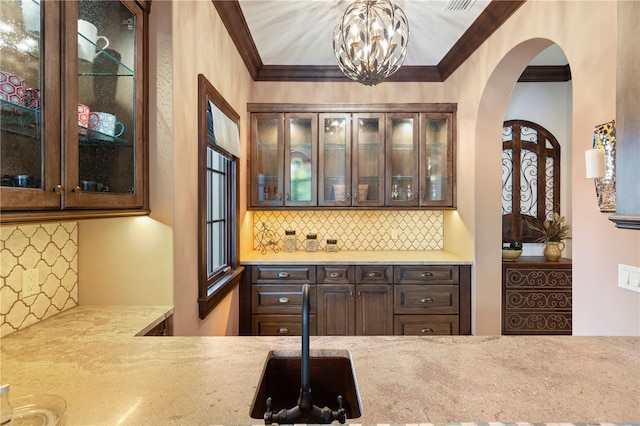 10138 Enchanted Oak Dr, Golden Oak, FL 32836 - bar with an inviting chandelier, arched walkways, crown molding, and backsplash