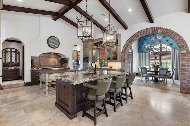 10138 Enchanted Oak Dr, Golden Oak, FL 32836 - kitchen featuring high vaulted ceiling, an inviting chandelier, arched walkways, a kitchen island with sink, and a sink