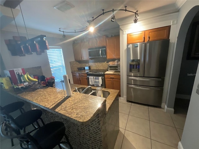 2737 Merrieweather Ln, Kissimmee, FL 34743 - kitchen with a sink, appliances with stainless steel finishes, brown cabinetry, backsplash, and a breakfast bar area