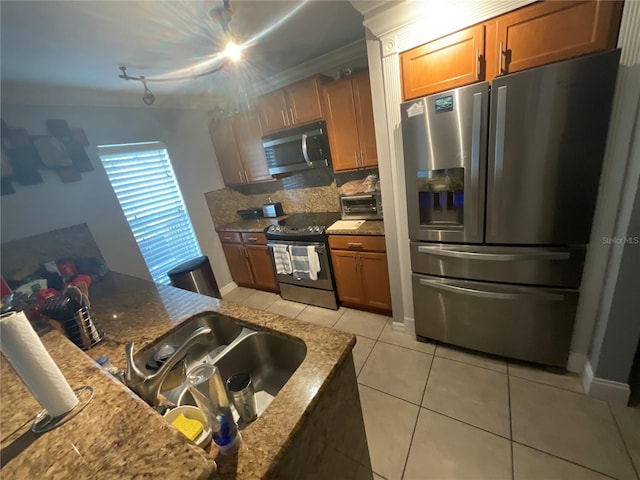 2737 Merrieweather Ln, Kissimmee, FL 34743 - kitchen with appliances with stainless steel finishes, light tile patterned floors, brown cabinets, decorative backsplash, and a sink