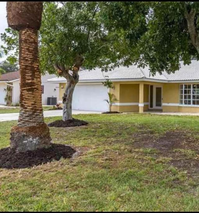 view of front facade featuring stucco siding, a front yard, an attached garage, and a tile roof