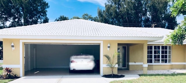 view of front of home with driveway, stucco siding, an attached garage, and a tile roof