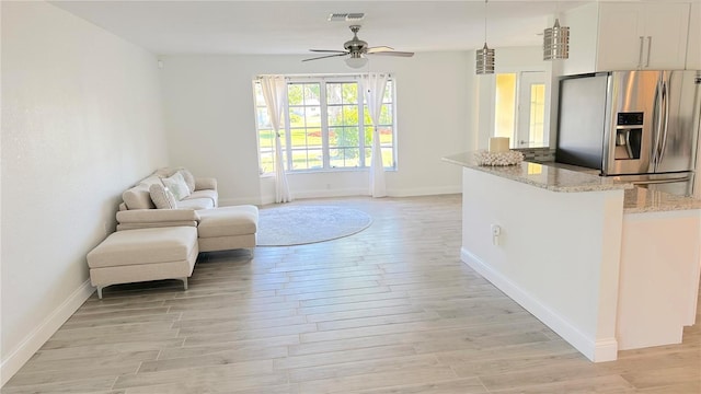sitting room with a ceiling fan, baseboards, and light wood-style floors