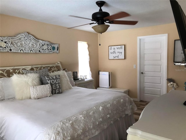 bedroom featuring wood finished floors, a ceiling fan, and baseboards