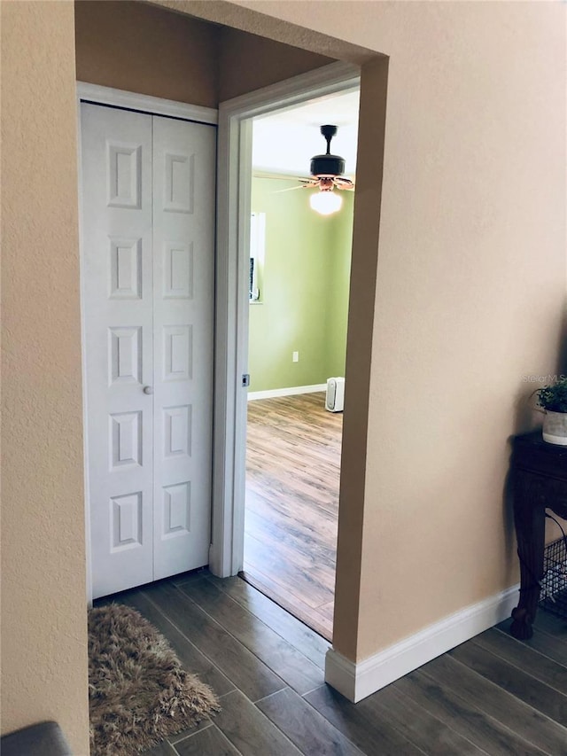 corridor featuring dark wood finished floors and baseboards
