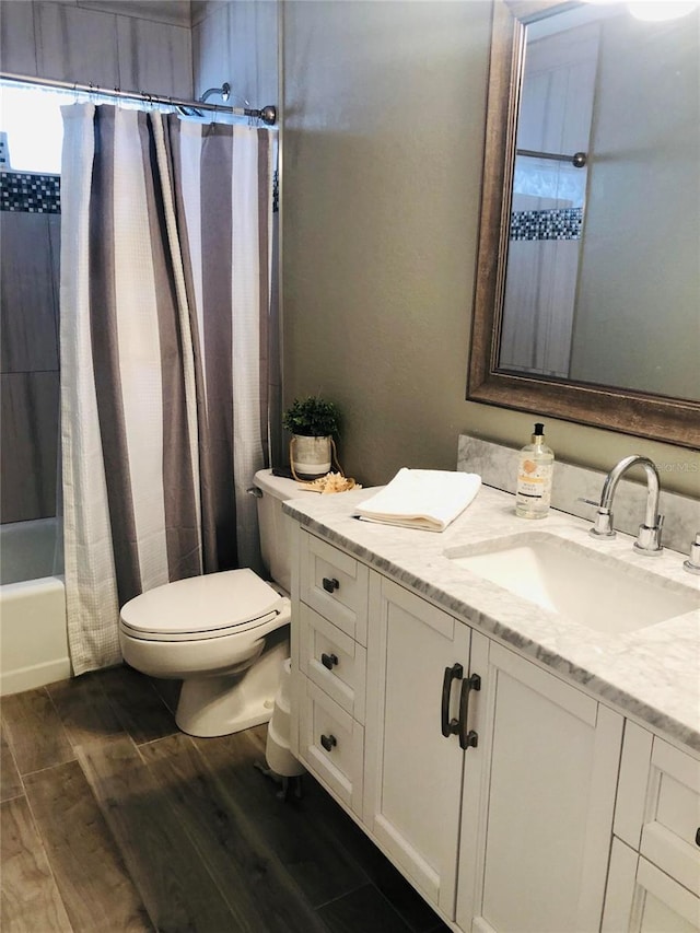 bathroom with toilet, vanity, wood finished floors, and shower / bath combo