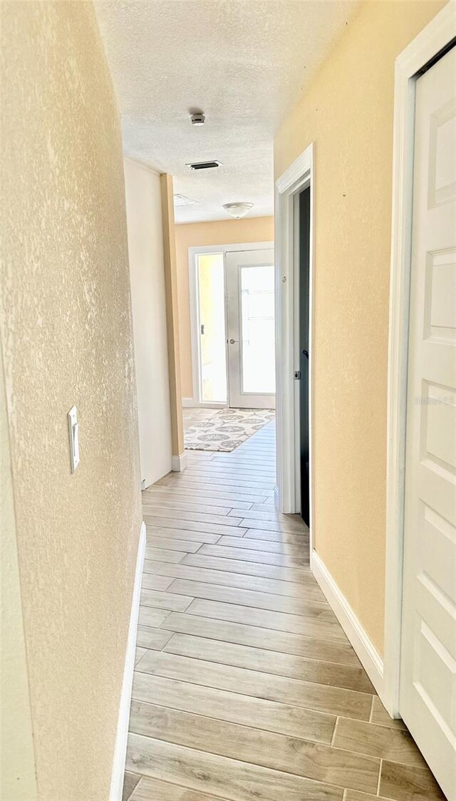 201 Chardin Dr, Nokomis, FL 34275 - corridor featuring light wood-style flooring, a textured wall, and a textured ceiling