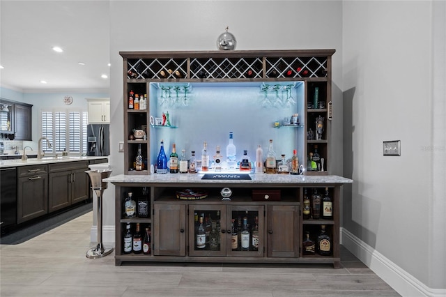 10662 Woodchase Cir, Orlando, FL 32836 - bar with crown molding, baseboards, a sink, a bar, and light wood-style flooring