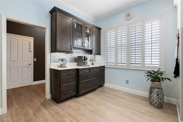 10662 Woodchase Cir, Orlando, FL 32836 - kitchen with decorative backsplash, light countertops, crown molding, dark brown cabinets, and light wood-type flooring