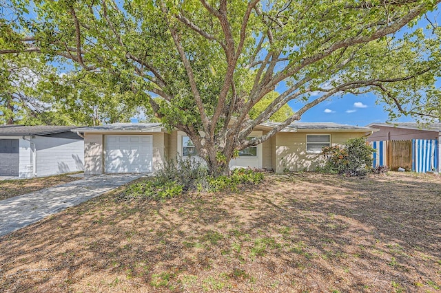 view of front of property with brick siding, an attached garage, driveway, and fence