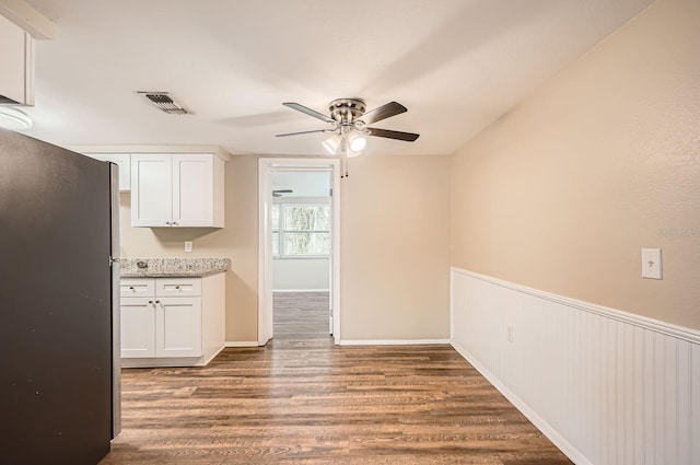 kitchen with a ceiling fan, visible vents, wood finished floors, white cabinets, and freestanding refrigerator