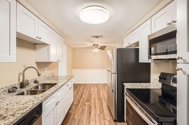 kitchen with visible vents, white cabinetry, a sink, light wood finished floors, and stainless steel appliances
