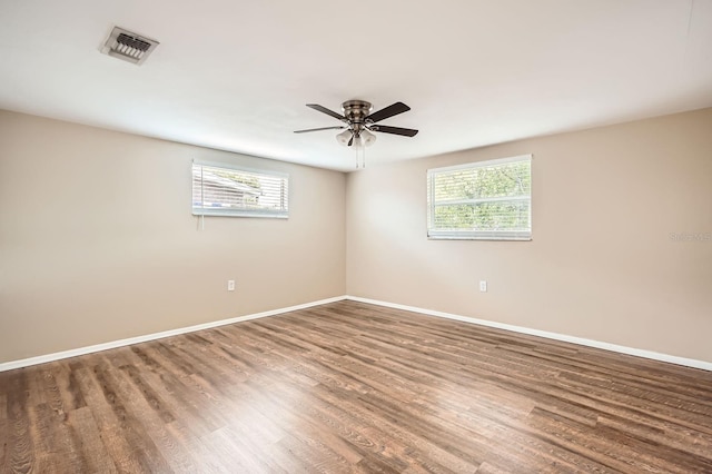 unfurnished room featuring baseboards, visible vents, a wealth of natural light, and wood finished floors