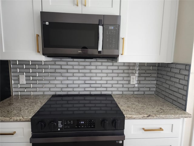 101 Dovetail Ct, Apopka, FL 32703 - kitchen view of black range oven, decorative backsplash, white cabinets, and light stone counters