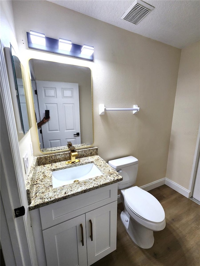 101 Dovetail Ct, Apopka, FL 32703 - bathroom with wood finished floors, vanity, toilet, a textured ceiling, and baseboards