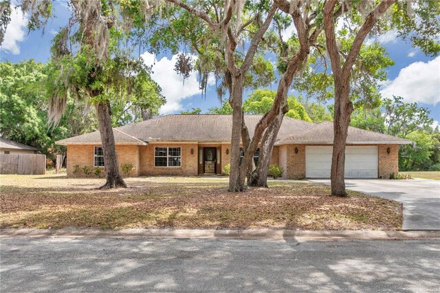 ranch-style home featuring driveway, brick siding, a garage, and fence