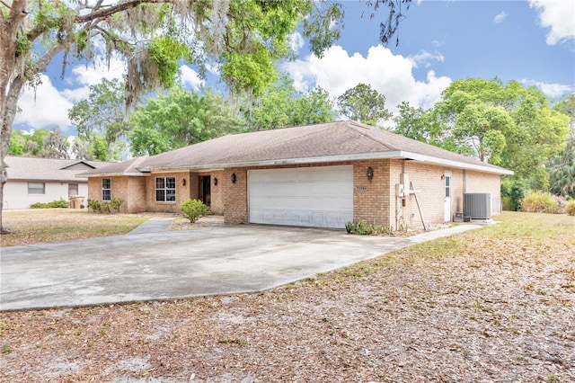 single story home featuring brick siding, driveway, central air condition unit, and an attached garage